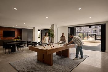 A man is playing pool in a room with a woman watching.